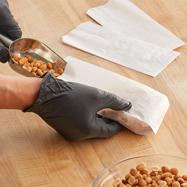 A person in gloves putting peanuts into a Kari-Out plain glassine bag.