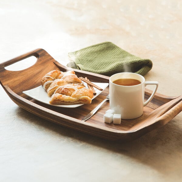 An Ironwood acacia wood room service tray with a cup of tea and a pastry on it.