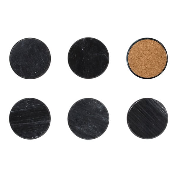 A group of six black marble coasters with white specks on cork board.