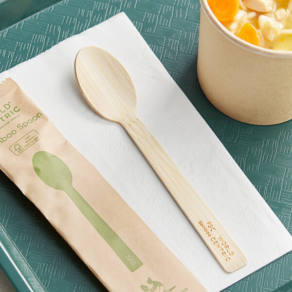 A World Centric compostable bamboo spoon on a napkin next to a cup of soup.