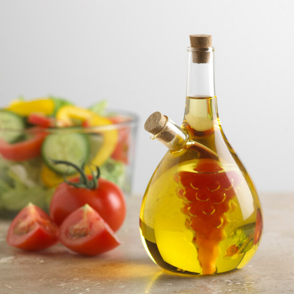 A glass oil cruet with a cork next to a vegetable salad.