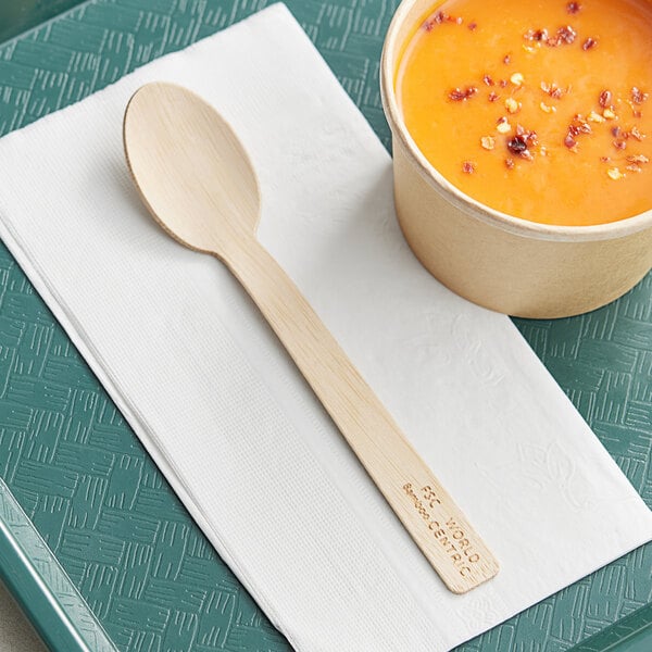 A bowl of soup and a World Centric compostable bamboo spoon on a tray.