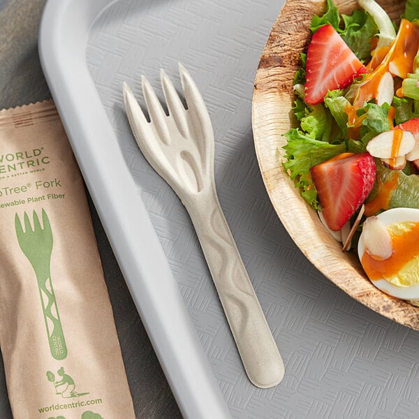 A bowl of salad with a World Centric compostable fiber fork on a table.