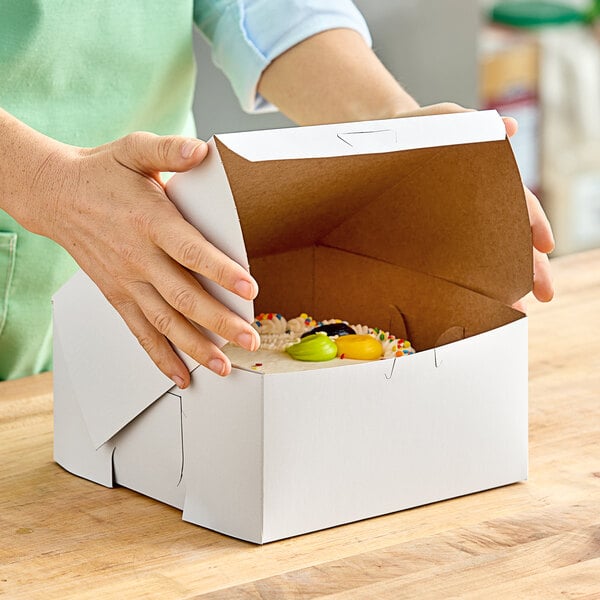 A person's hand opening a white Southern Champion cake box.