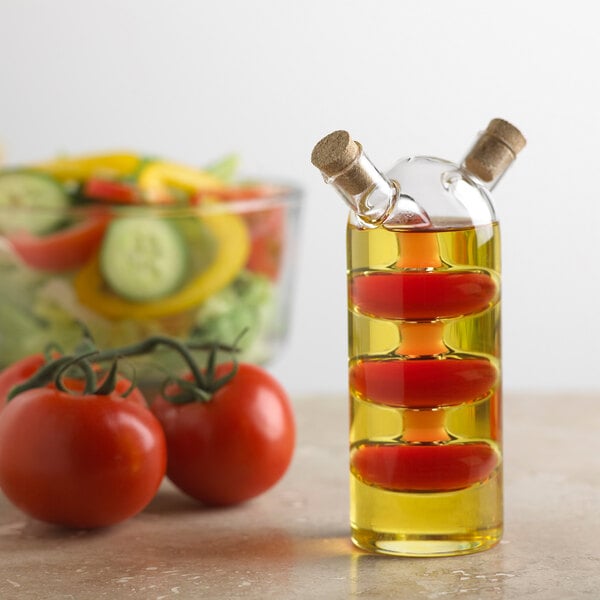 A CRUET OIL/VIN bottle filled with olive oil next to tomatoes.
