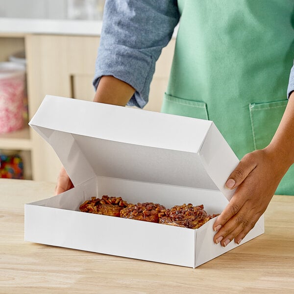 A person holding a white Southern Champion donut box.