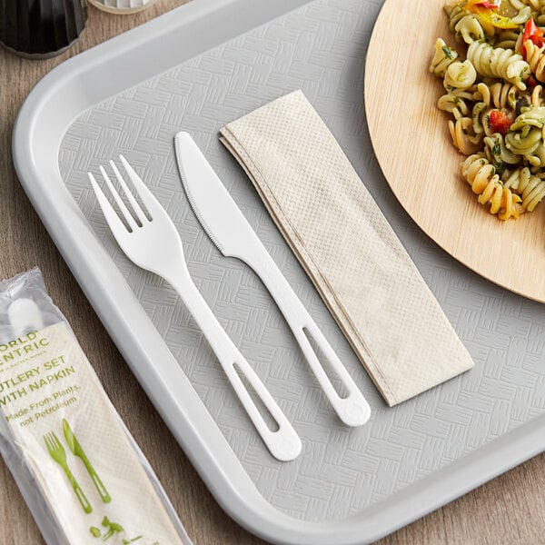 A tray with a white World Centric compostable fork and knife and a napkin.