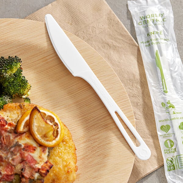 A World Centric compostable TPLA knife on a wooden plate with a fork.