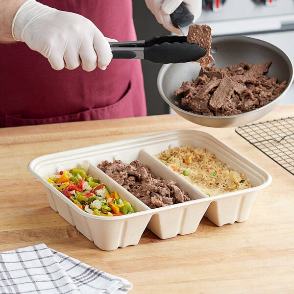 A person using a World Centric 3-compartment catering tray to serve food.