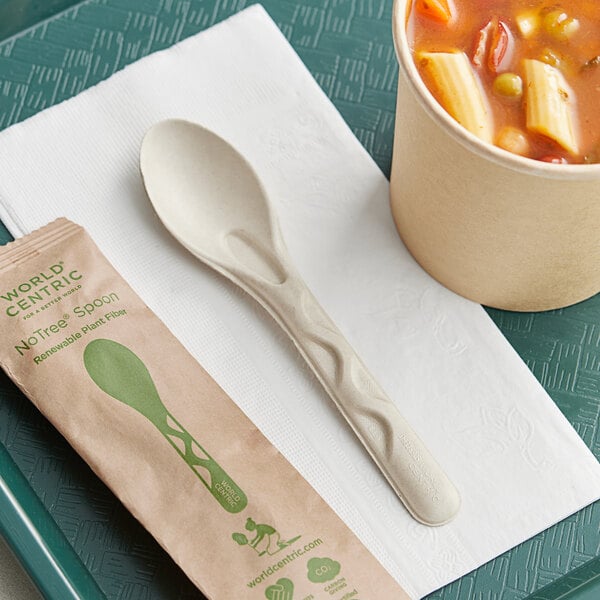 A tray with a bowl of soup with pasta and vegetables and a spoon wrapped in a napkin.