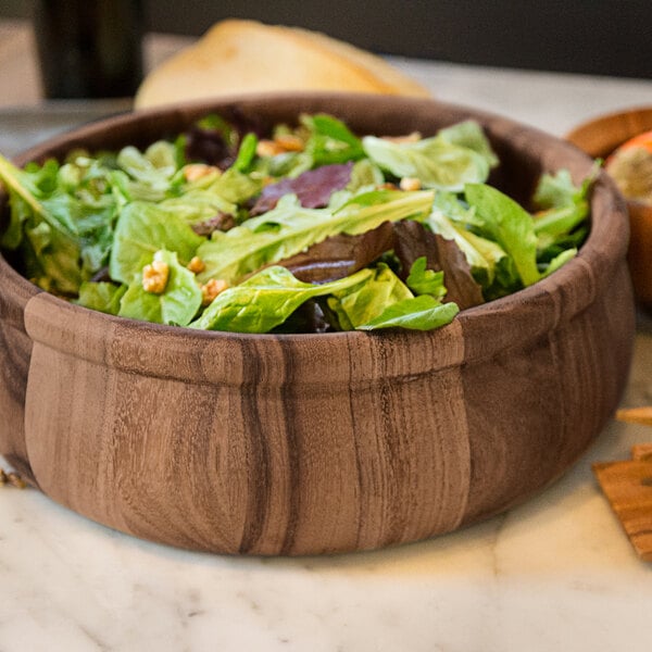 An Ironwood acacia wood salad bowl filled with salad on a table.