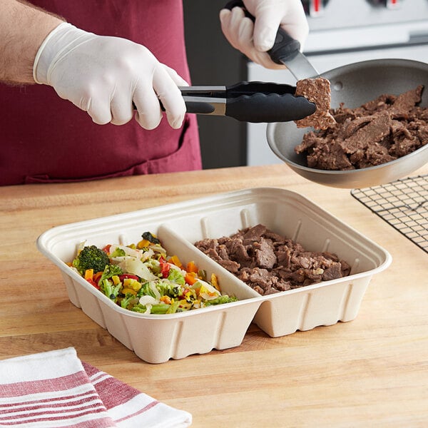 A hand in a white glove using tongs to place meat in a World Centric compostable catering tray.