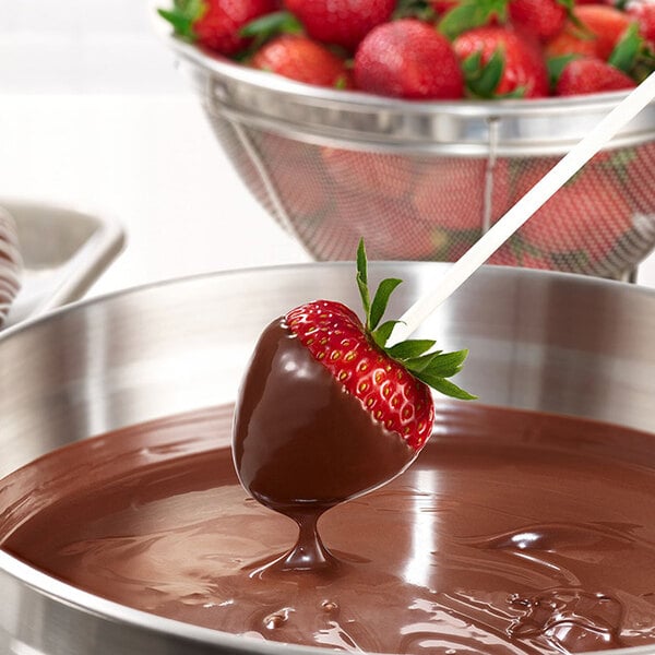 A strawberry dipped in Ghirardelli dark chocolate on a counter.