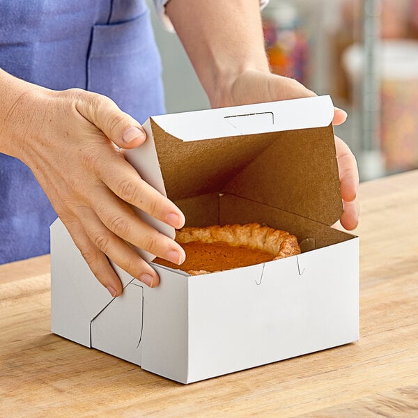 A person opening a white Southern Champion pie box to reveal a pie.