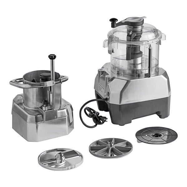 A commercial food processor with a clear plastic bowl, continuous feed attachment, and multiple metal discs.