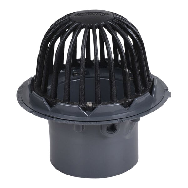 A grey PVC roof drain with a black cast iron dome guard.