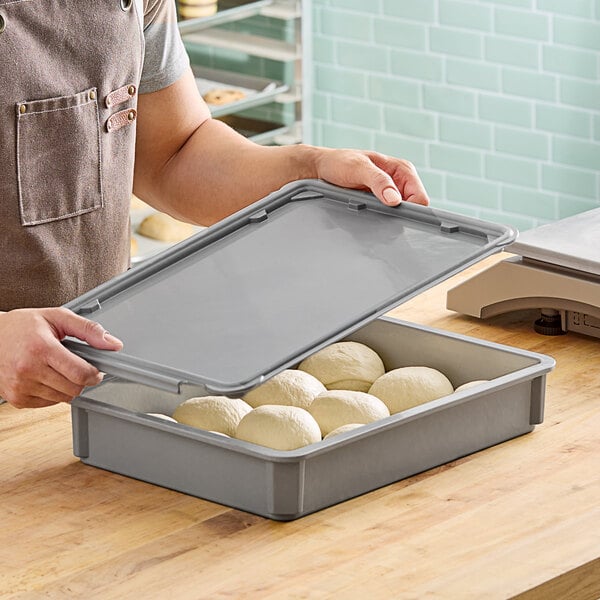 A person putting dough in a MFG Tray mini dough proofing box lid.