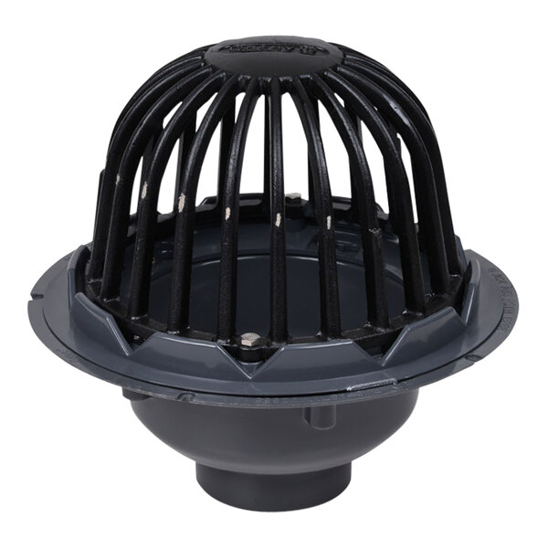 A grey PVC roof drain with a black cast iron dome guard.