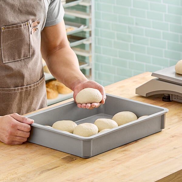 A man holding dough in a MFG Tray fiberglass dough proofing box.