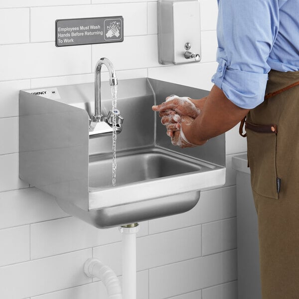 A person washing their hands in a Regency wall-mounted hand sink.