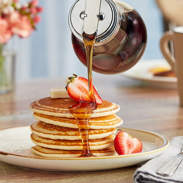 Mrs. Butterworth's Original Breakfast Syrup being poured onto a stack of pancakes.