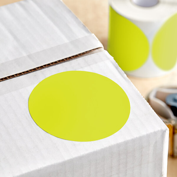 A box with a yellow circle on it next to a roll of Lavex toilet paper.