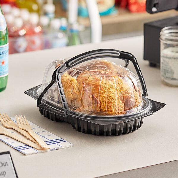 A plastic container with a Pactiv black chicken roaster inside.