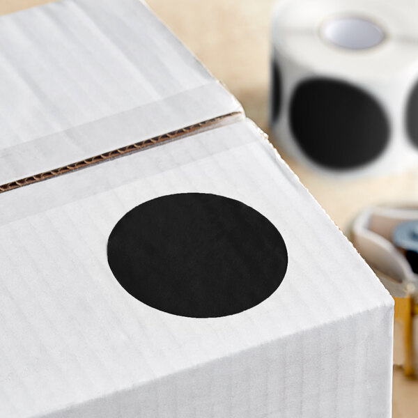 A white box with a roll of black semi-gloss paper labels with black circles on it.