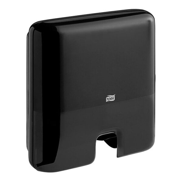 A black Tork mini wall-mount multifold hand towel dispenser with a handle.