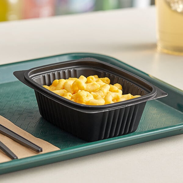 A black Pactiv MicroMax deli container filled with macaroni and cheese on a table.