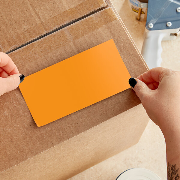 A person's hand holding a yellow rectangular Lavex inventory label.