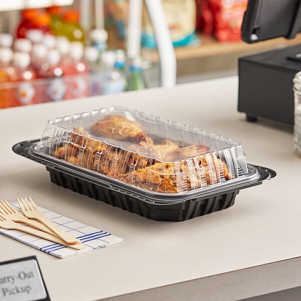 A tray of chicken in a Pactiv black chicken barn on a counter.