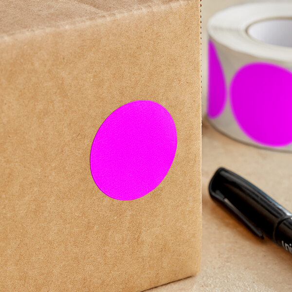 A brown box with a roll of Lavex pink round stickers on it.