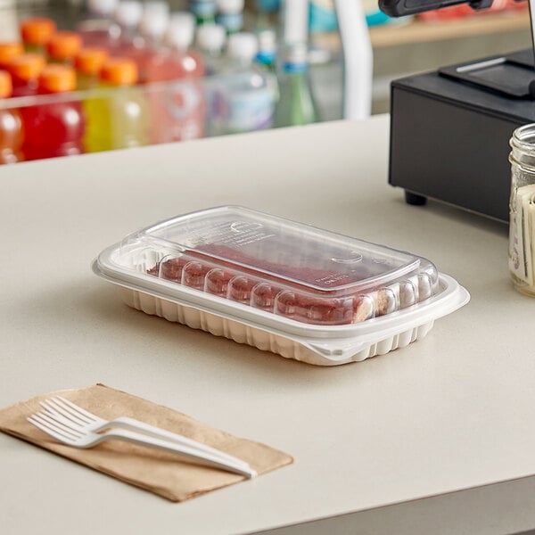 A Pactiv plastic container of food on a deli counter with a pair of plastic forks.