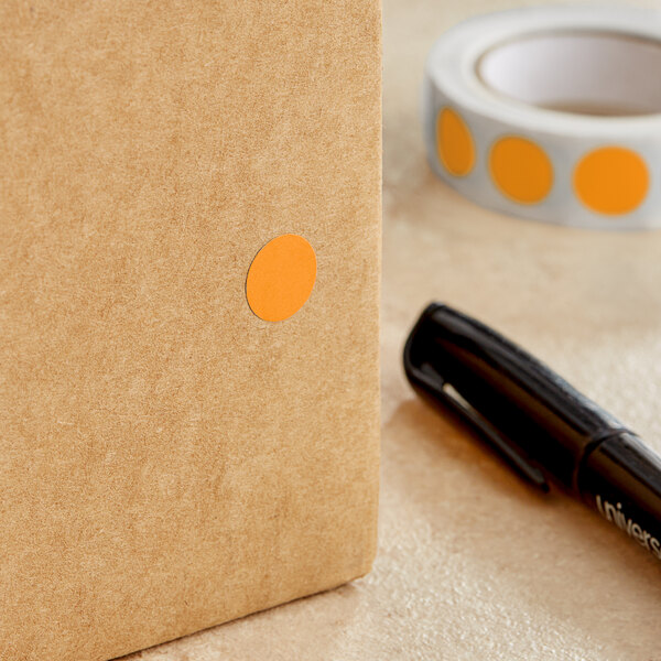 A roll of Lavex fluorescent orange round inventory labels with semi-gloss paper and a small orange circle on a brown surface.