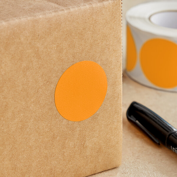 A brown box with a Lavex orange round sticker on it next to a black pen.