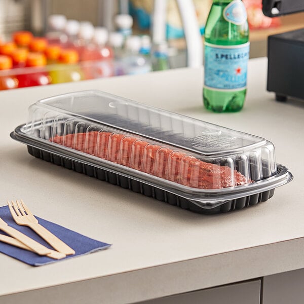 A tray of meat in a Pactiv black plastic container with a clear lid.