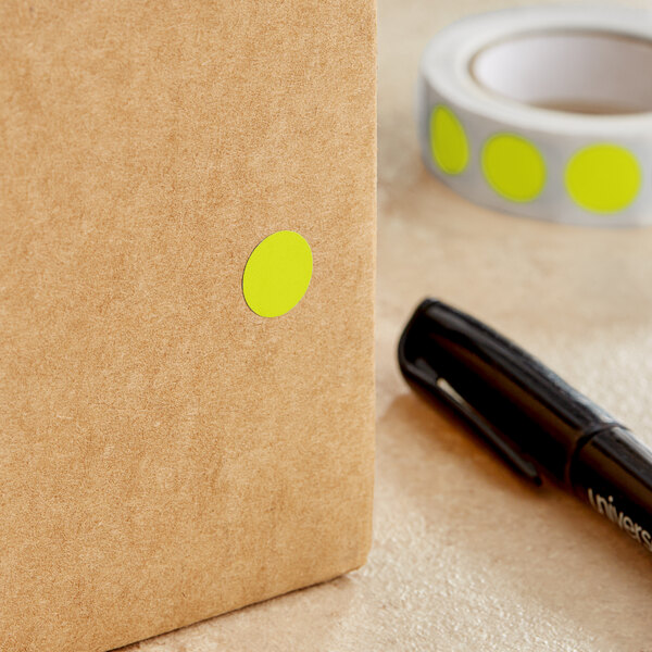 A roll of Lavex fluorescent chartreuse inventory labels with yellow circles on a brown surface.