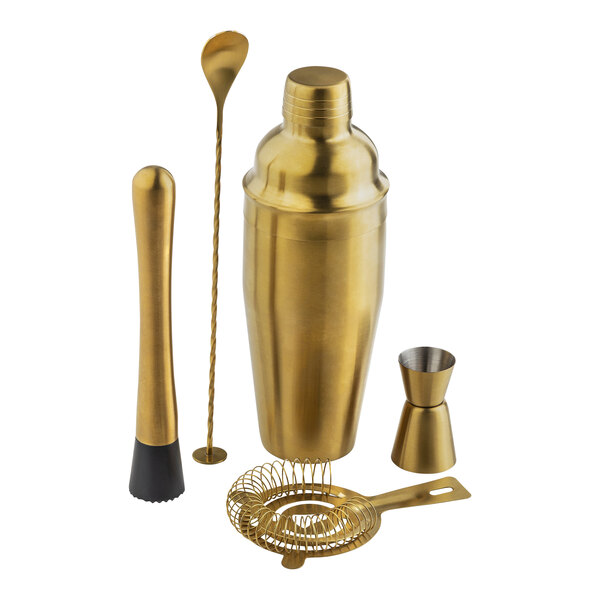 A gold cocktail shaker, metal spoon, and bar tools.