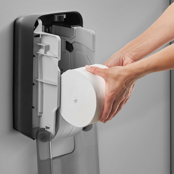 A person's hands holding a Tork OptiServe toilet paper roll.