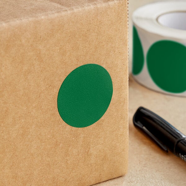 A brown box with a green circle on it next to a roll of Lavex paper labels.