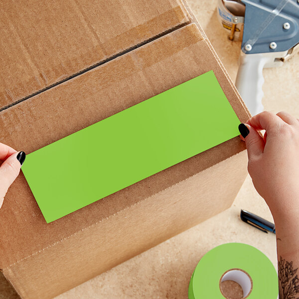 A person's hands using a green rectangular Lavex label.