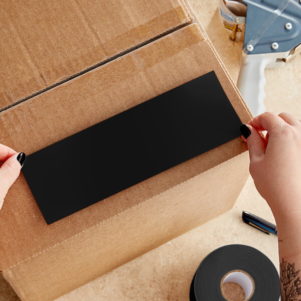 A person's hands holding a black rectangular Lavex inventory label.