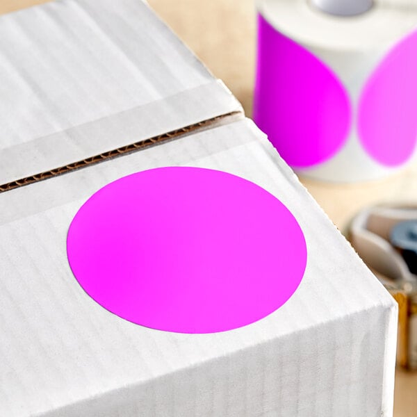 A box with a white label and a roll of Lavex pink round inventory labels.