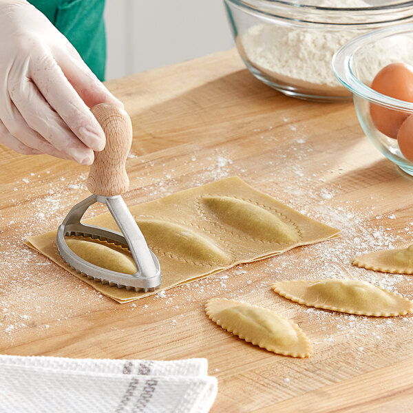 A person using an Imperia oval ravioli cutter to make pasta.