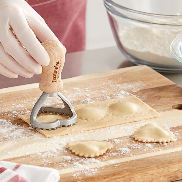 A person using a Imperia metal heart-shaped cutter to make ravioli.