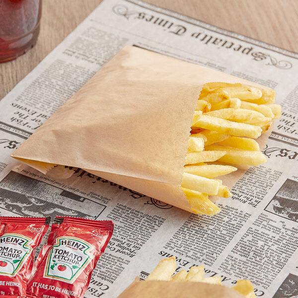 A Bagcraft EcoCraft natural paper bag filled with french fries on a newspaper.