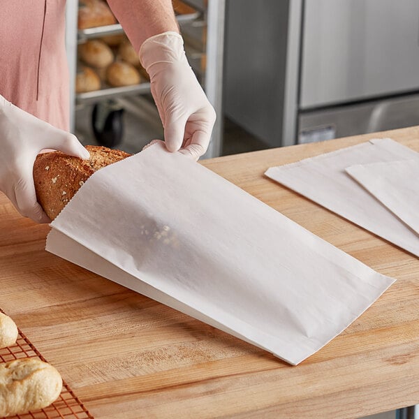 A person in gloves holding a Bagcraft Dubl Wax white bread bag.