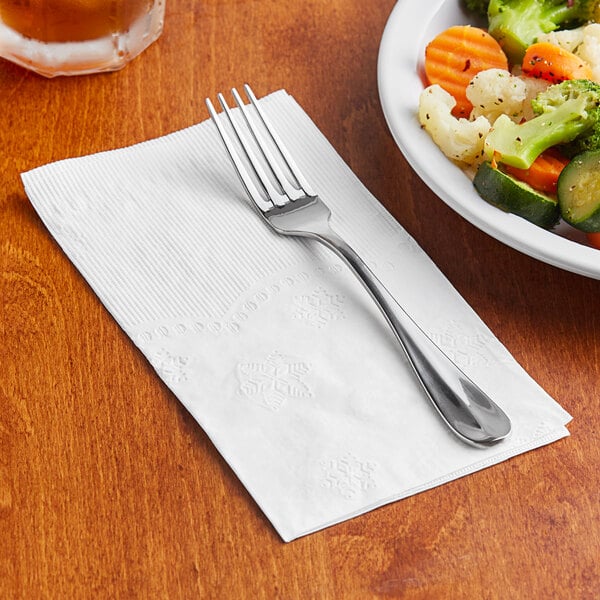 A fork on a Morcon Valay 2-ply white dinner napkin next to a plate of vegetables.