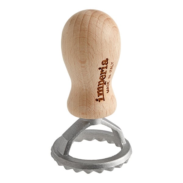 A wooden Imperia ravioli cutter with a round metal object.